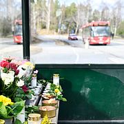 Blommor och ljus i en busskur vid platsen som 18-åringen dödades på.