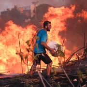 En volontär hjälper till att släcka en brand norr om Aten. 