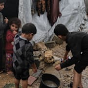 En familj sörjer sina släktingar som dödades i ett israeliskt anfall mot sjukhuset Shifa under vapenvilan. Till höger försöker barn tömma vatten ur sitt tält som översvämmats i Gaza.