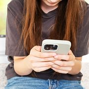 En ung person använder sin telefon, illustrationsbild.