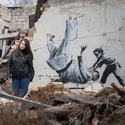 En ukrainsk kvinna förevigas framför ett av Banksys verk. Andrew Kravchenko / AP