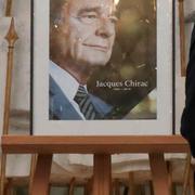 Människor skriver sina kondoleanser framför ett foto på Jacques Chirac