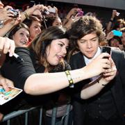 En ung Harry Styles tar en bild med ett fan år 2012.