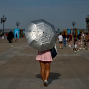 Kvinna skyddar sig mot solen med ett paraply i Madrid, Spanien, i augusti 2025. 