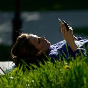 En kvinna i en park använder sin telefon.