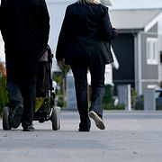 En man och en kvinna är ute på promenad med sitt barn i barnvagn i ett nybyggt villaområde. Illustrationsbild.