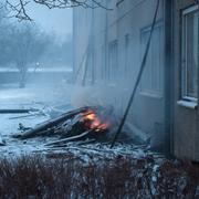 Uppbrunna delar ligger på marken vid det flerfamiljshus i Eslöv där en kraftig brand rasade på lördagsmorgonen