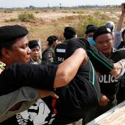 Polis griper demonstranter utanför fängelset i Phnom Penh.