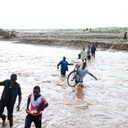 People wade through floodwaters in the aftermath of Tropical Cyclone Freddy in Phalombe, southern Malawi on March 18, 2023.