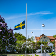 Flagga på halv stång och blommor utanför skolan.