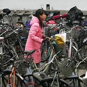 Cykel är ett mycket populärt färdmedel i Kina. Arkivbild: Kvinna på cykelparkering i Peking.