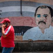 En man går förbi en vandaliserad väggmålning av Nicaraguas president Daniel Ortega i Managua. 