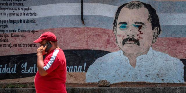 En man går förbi en vandaliserad väggmålning av Nicaraguas president Daniel Ortega i Managua.  INTI OCON / TT NYHETSBYRÅN