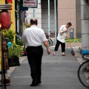 A worker sweeps a restaurant street before lunch time Thursday, Aug. 17, 2023, in Tokyo. 