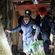 En äldre kvinna leds ut ur ett bombat hus i Zaporizjzja i sydöstra Ukraina.