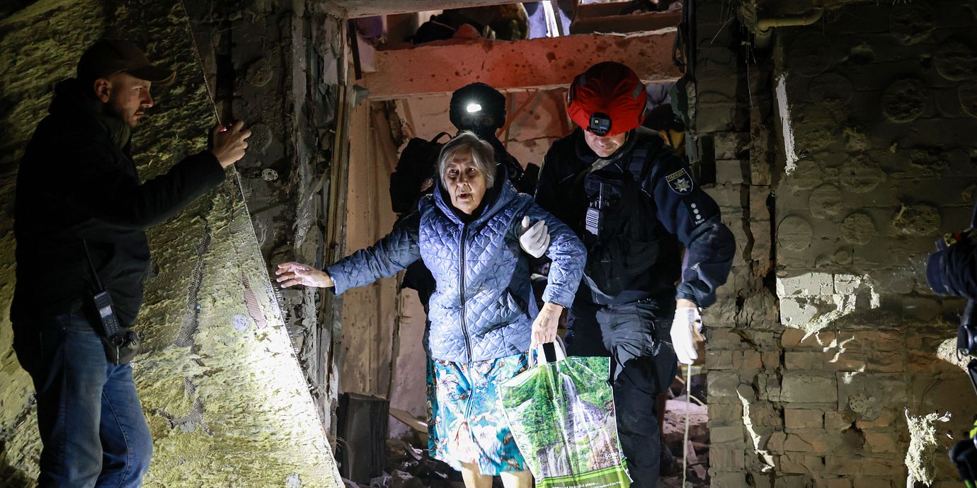 En äldre kvinna leds ut ur ett bombat hus i Zaporizjzja i sydöstra Ukraina.