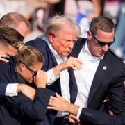 Donald Trump förs i säkerhet av Secret service efter att ha träffats av ett skott i örat under ett kampanjmöte 13 juli. 