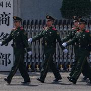 Paramilitära soldater och en polis med en spårhund marscherar vid huvudingången till Kinas handelsdepartement i Peking. Arkivbild.
