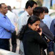 Kontorsarbetare står på gatan efter att ha utrymt byggnader i New Delhi på grund av skalvet