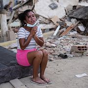 En kvinna gråter bredvid rasmassorna av en byggnad i Venezuela.