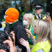 DJ Próvaí i Kneecap stöttar bandmedlemmen Mo Chara utanför domstolen i London. 