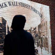 En man står framför en väggmålning som förestället Black Wall Street före rasistattacken som förstörde hela distriktet, i Greenwood i Tulsa, Oklahoma. 