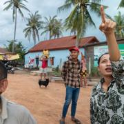 En invånare i Samraong, huvudstaden i Oddar Meanchey-provinsen i Kambodja, pekar på var hon ser ett flygplan som beskjuts av kambodjanska styrkor fredagen den 25 juli.