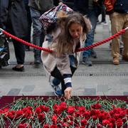 En kvinna lämnar blommor vid platsen för dådet