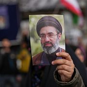 En demonstrant håller upp Mojtaba Khameneis porträtt.