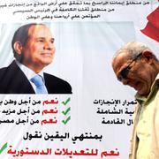 En man framför en affisch på Egyptens president t Abdel Fattah al-Sisi.