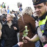 En flicka ger polisen en blomma vid manifestationen på Sergels Torg i Stockholm.