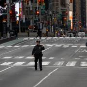 En polis på ett folktomt Times Square i New York.