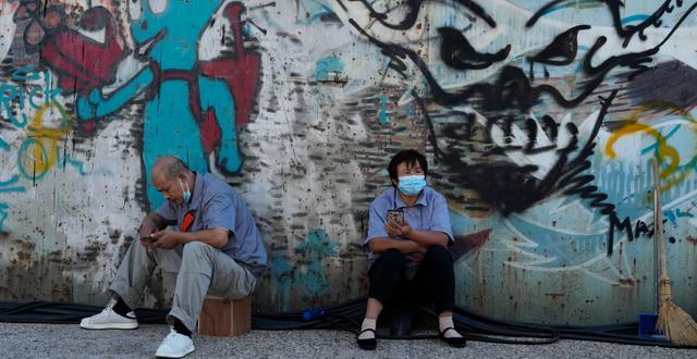 Illustrationsbild. Två personer sitter under en grafittimålning i Peking, september 2022.  Ng Han Guan / AP