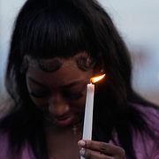 Kvinna tänder ett ljus under en bön för offren. 