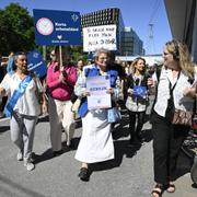 Vårdförbundets ordförande Sineva Ribeiro (mitten) demonstrerar tillsammans med vårdpersonal utanför Karolinska sjukhuset.