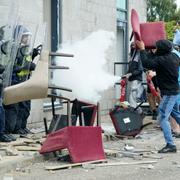 Demonstranter slänger stolar på polis i samband med kravallerna i England i helgen.