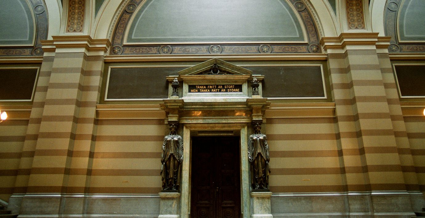 Texten ”Tänka fritt är stort men tänka rätt är större” över ingången till aulan i Uppsala universitetshus.