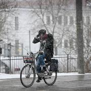 Arkivbild på en cyklande kvinna i snöfall. 