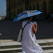 En kvinna skyddar sig från solen med ett paraply i Paris.