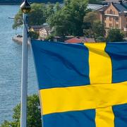 Svenska flaggan med Stockholm i bakgrunden.