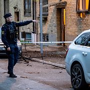 Polis och kriminaltekniker undersöker skadorna på fasaden och parkerade fordon efter en explosion vid en fastighet på Hindby i Malmö tidigt på söndagen.