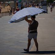 En man tar skydd från solen i Barcelona. Bilden är tagen i maj.