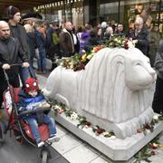 På årsdagen av terrordådet på Drottninggatan i Stockholm lägger människor blommor på betonglejonen vid det hörn av Åhléns City som Rakhmat Akilovs kapade lastbil kraschade in i. 