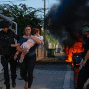 Polis evakuerar en kvinna och ett barn i Ashkelon i södra Israel efter ett raketanfall från Gazaremsan, 7 oktober. 