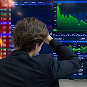 Illustrationsbild. En man står framför en skärm med aktiekurser som går ner.