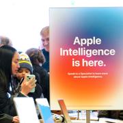 Människor kollar Iphones i en butik i USA. På en skylt syns reklam för Apples AI-assistent Apple intelligence.