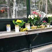 Blommor och ljus i busskuren vid den hållplats i Tyresö där en man i 18-årsåldern blev skjuten på en buss och sedan avled på onsdagen.