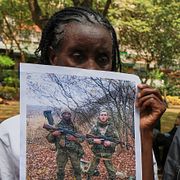 Familjemedlemmar till kenyaner som tros ha lurats att strida för Ryssland håller upp bilder 