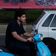 En ung man i Teheran kör förbi en vägg med porträtt av iranska kärnenergiforskare och militära ledare som dödades i israeliska attacker i juni. 