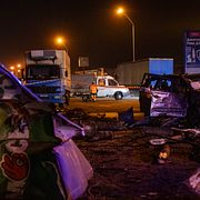 Räddningspersonal röjer bråte och skadad väginfrastruktur intill en förstörd bil efter en rysk attack mot Kyjiv under natten mot tisdagen.